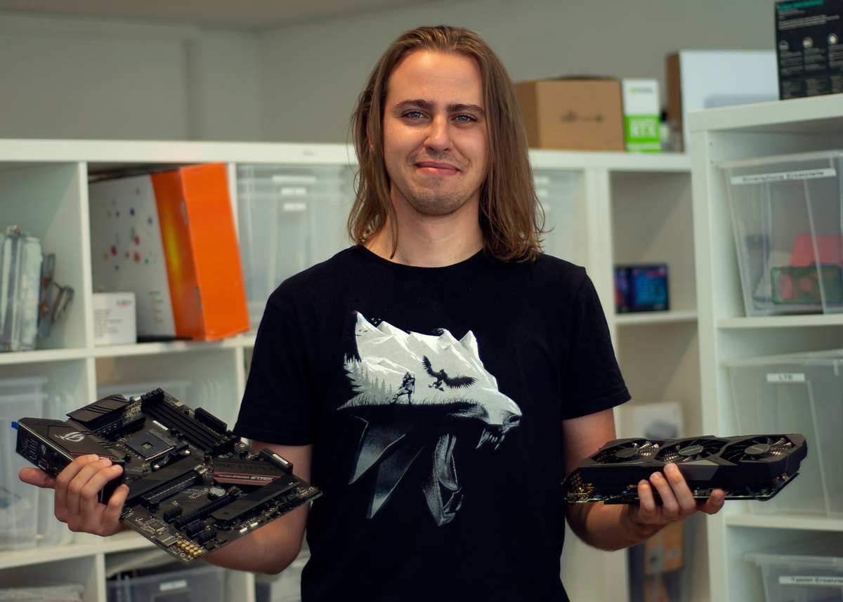 Techniker Edvinas hält ein Mainboard und eine Grafikkarte
