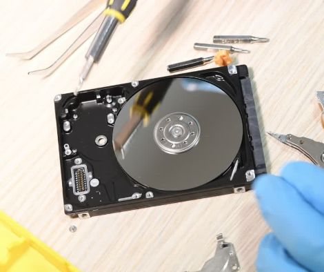 Geöffnete Festplatte mit Werkzeugen und sichtbarer Magnetscheibe