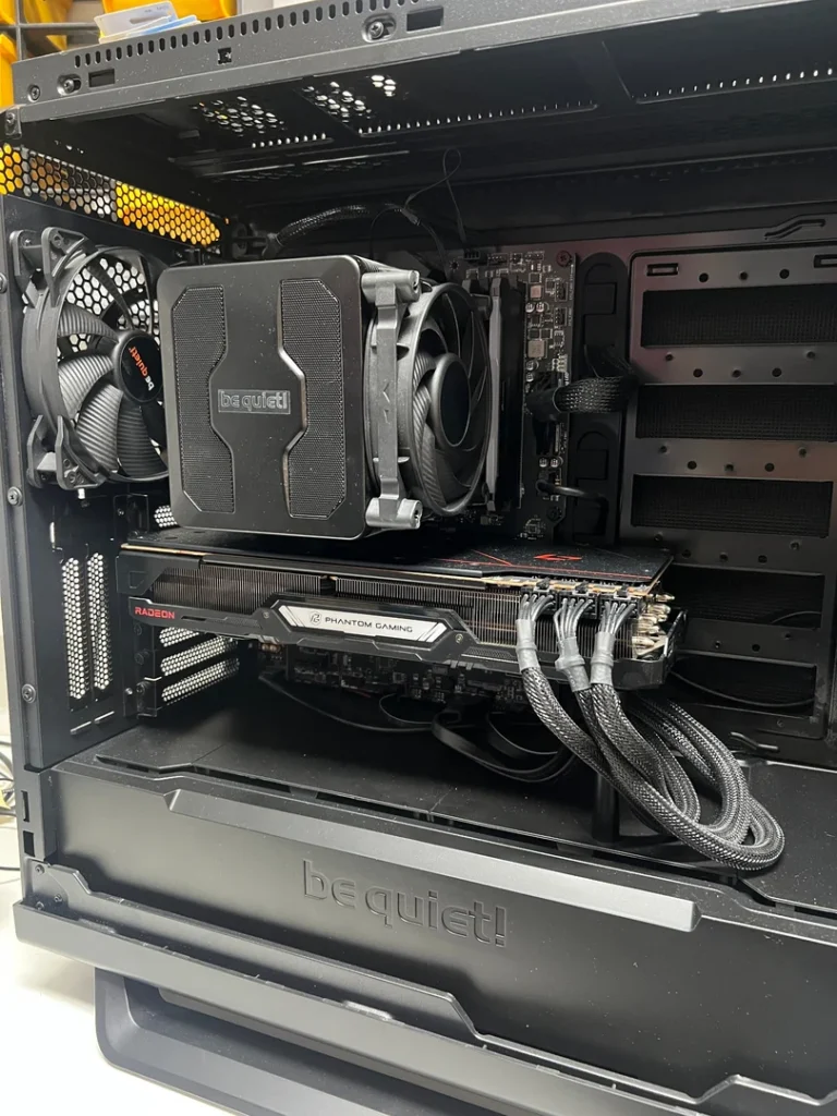 Geöffneter Gaming-PC mit sichtbarer Grafikkarte, Prozessorkühler und Staubablagerungen