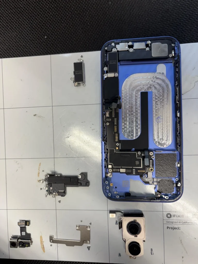 Geöffnetes iPhone 16 mit ausgebauten Kameras, Abdeckungen und weiteren Komponenten