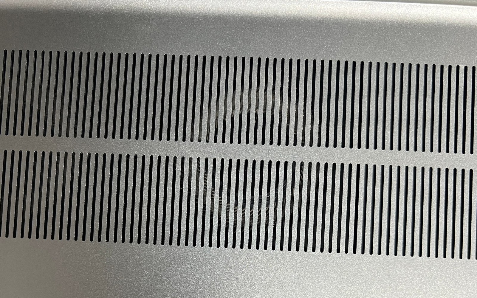Nahaufnahme der Unterseite eines Laptops mit Haaren hinter den Lüftungsschlitzen